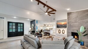 A spacious living area with a modern sofa, a dining table, and a kitchen in the background. - Lux Dallas Oasis- Pool, Hot Tub, Firepit, Game Room, Sleeps 12 (Dallas)