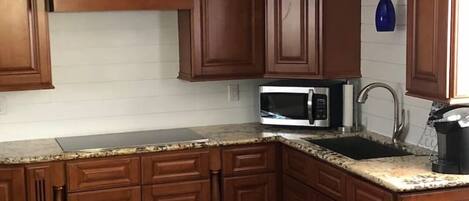 A kitchen with wooden cabinets, a microwave, and a sink.