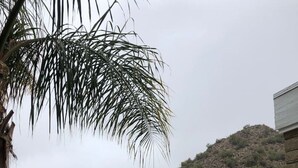Zona de piscina con vista a una montaña, un patio con sillas y piscina cercada.