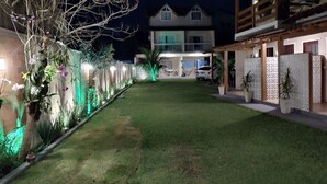 A well-maintained garden with a lawn, decorative plants, and a pathway leading to a building with a balcony.