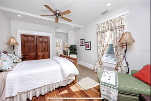 Relax in this inviting bedroom with a large bed, sofa, and ceiling fan.