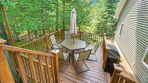 A wooden deck with a table and chairs, surrounded by trees.
