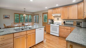 A kitchen with wooden cabinets, granite countertops, a dishwasher, a stove, and a microwave.