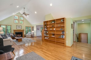 Cozy living room with a fireplace, ceiling fan, and large bookshelf.