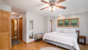 A bedroom with a bed, a ceiling fan, a window, and a door.
