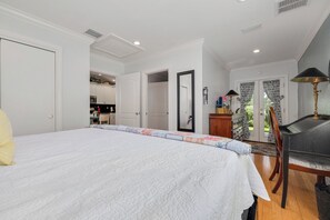 Un dormitorio con una cama grande, una silla, un escritorio y vistas a la cocina.