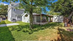 A two-story house with a covered patio, a fenced yard, and a tree in the foreground. - Downtown Dunedin Cozy 1 bedroom Cottage (Dunedin)