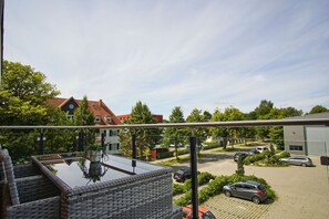 A balcony with a view of a residential area, including houses and parked cars. - Near the marina, balcony, private sauna - Alte Fischfabrik Lauterbach, Vacation Apartment No. 10 (Putbus)
