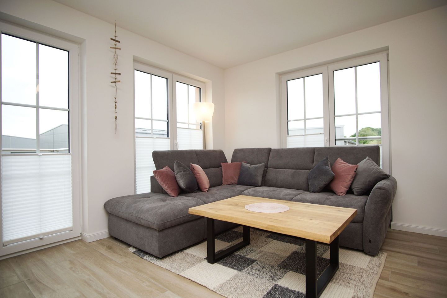 A modern living room with a grey sectional sofa, a wooden coffee table, and a patterned rug.