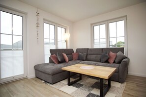 A modern living room with a grey sectional sofa, a wooden coffee table, and a patterned rug.