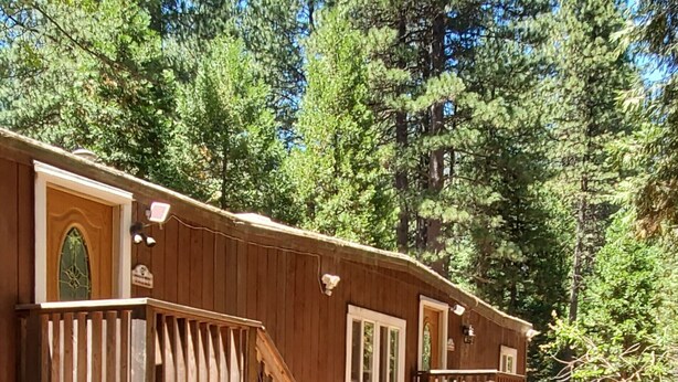 Une cabane en bois dotée d’un balcon, d’un espace salon extérieur et d’une lanterne.