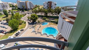 Un immeuble de grande hauteur doté d’une piscine, de plusieurs balcons et offrant une vue sur la mer.