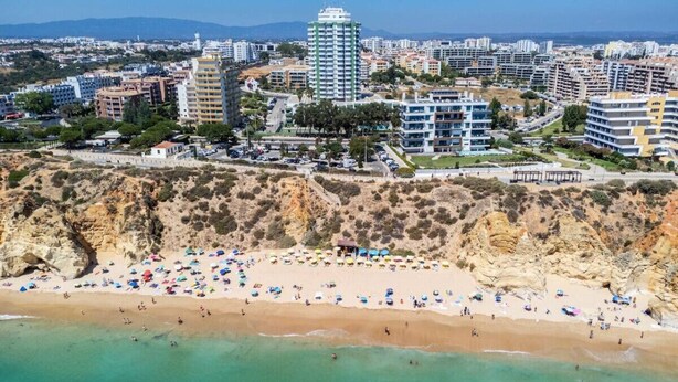 Vue aérienne d’une zone côtière avec une plage, des bâtiments et des falaises.