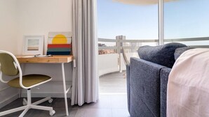 Une chambre d’hôtel équipée d’un bureau, d’une chaise et offrant une vue sur la ville grâce à de grandes fenêtres.