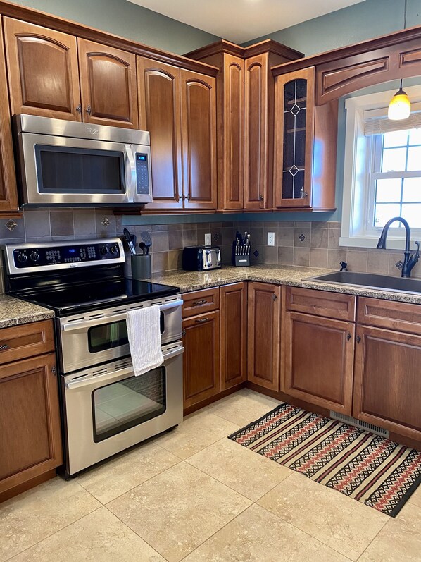 A kitchen with wooden cabinets, stainless steel appliances, a microwave, a toaster, and a sink. - SPORTSMAN'S PARADISE, 5 Bedroom Home in Fort Peck, Montana (Fort Peck)