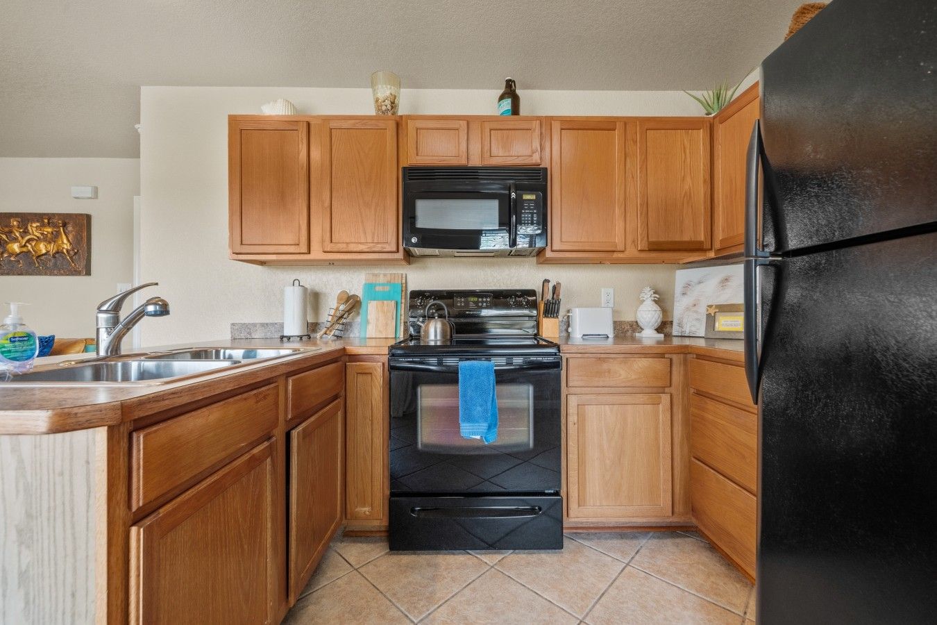 Una cocina con gabinetes de madera, una estufa negra, un microondas y un refrigerador.