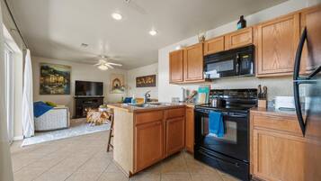 A kitchen with wooden cabinets, a black stove, a microwave, and a refrigerator.