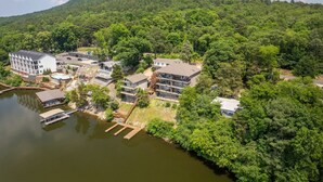 A lakeside property with multiple buildings, including a large white structure with a sloped roof and a smaller building with a flat roof.