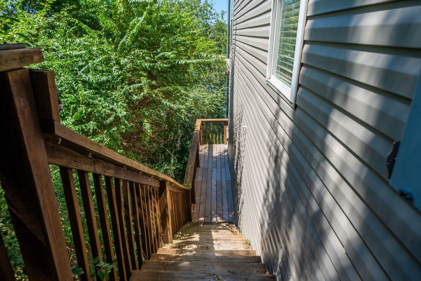 A wooden deck leading to a house with siding.