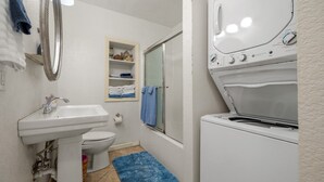 Une petite salle de bain comprenant un lavabo, des toilettes et un appareil combiné lave-linge et sèche-linge.