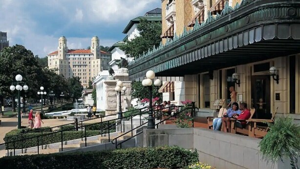 A historic building with a covered porch and a fountain in the foreground.