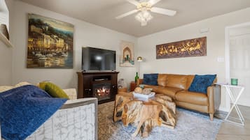 Una sala de estar con chimenea, sofá de cuero y televisor.