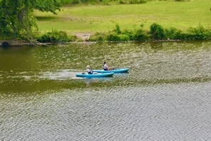 Une rivière paisible où flottent deux personnes dans un canoë bleu.