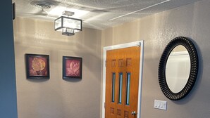 A hallway with a wooden door, framed pictures, a mirror, and a light fixture. - Beautiful home in Melbourne near the beach (Melbourne)