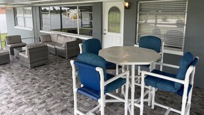 An outdoor patio with wicker furniture, a table, and chairs with blue cushions. - Beautiful home in Melbourne near the beach (Melbourne)