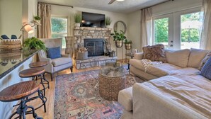 A cozy living room with a stone fireplace, comfortable seating, and a television. - Tranquil mountainhouse w/hot tub, super close to trails & wineries- pet friendly (Linden)