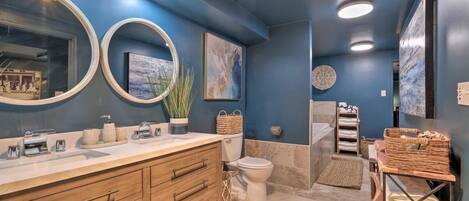 Une salle de bain moderne avec un mur d’accent bleu, un meuble-lavabo en bois, un grand miroir et un espace douche.