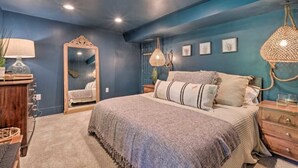 A bedroom with a large bed, a dresser, a mirror, and a hanging light fixture. - Tranquil mountainhouse w/hot tub, super close to trails & wineries- pet friendly (Linden)