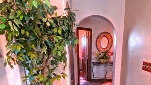 A hallway with a wooden floor, a potted plant, a mirror on the wall, and a door at the end. - Cozy Casita, overlooking Senoran Desert Peserve, Cave Creek (Phoenix)