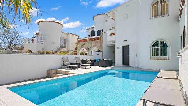 A swimming pool with lounge chairs, a stone wall, and a white building with arched windows. - WELCS VILLA 022 EMP La Morgana con piscina priva (Empuriabrava)
