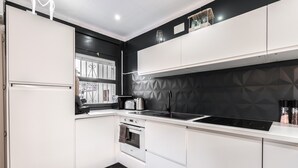 A modern kitchen with white cabinets, a black backsplash, a built-in oven, a stove, and a black induction cooktop. - WELCS VILLA 022 EMP La Morgana con piscina priva (Empuriabrava)