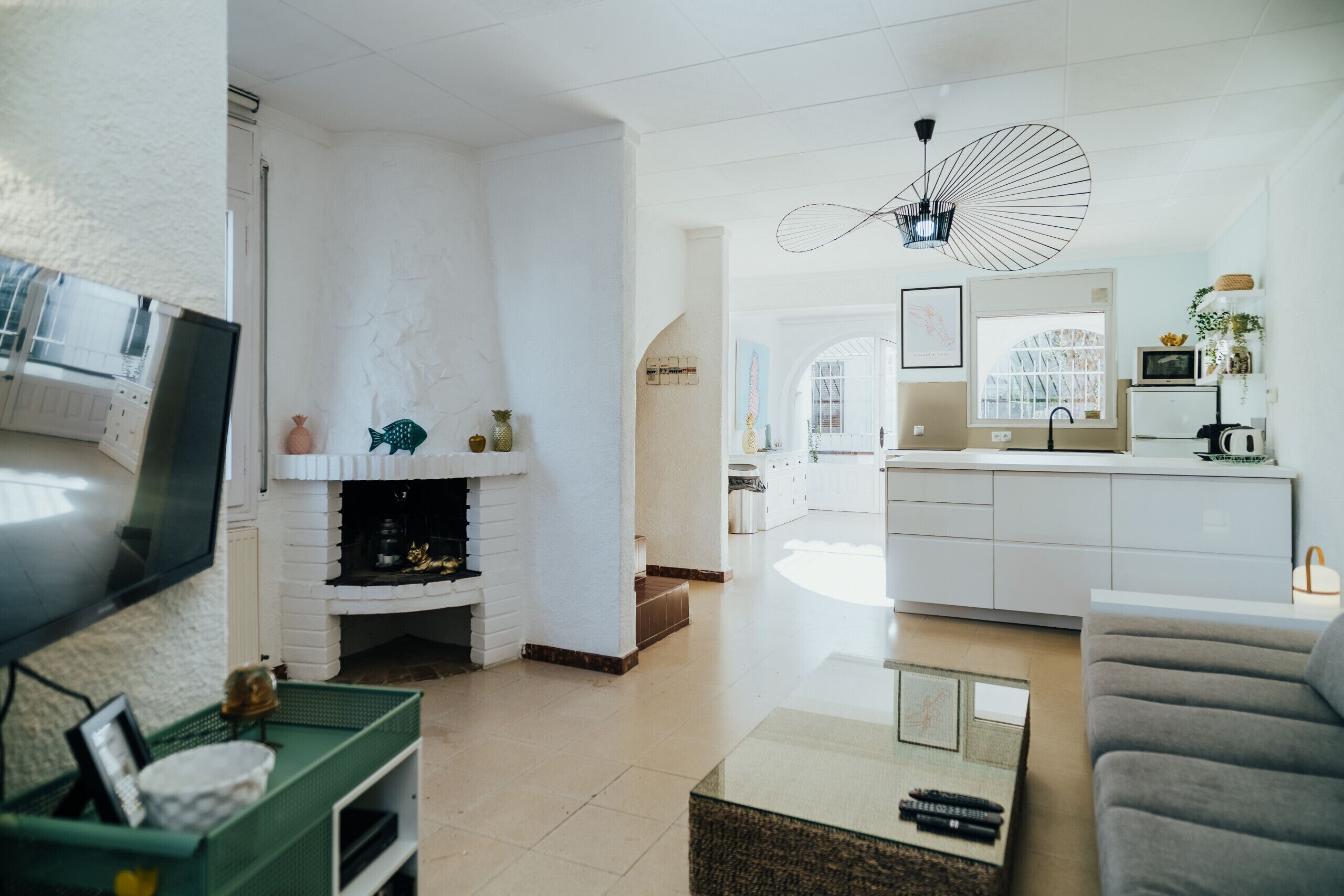 Een moderne woonkamer met een open haard, een televisie en een keuken in de achtergrond.