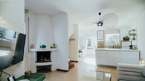 Un soggiorno moderno con camino, televisione e zona cucina sullo sfondo.