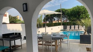 Patio esterno con piscina, barbecue e zona pranzo.