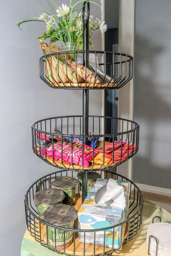 Shelf unit with a potted plant, snacks, and canned goods.