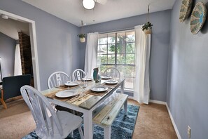 Enjoy a casual dining experience in this inviting room with a rustic table for four, surrounded by natural elements and soft lighting.