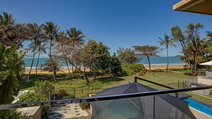 A residential property with a view of the beach, a swimming pool, and a fenced yard.