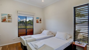A hotel room with two beds, a window with a view, and artwork on the walls.