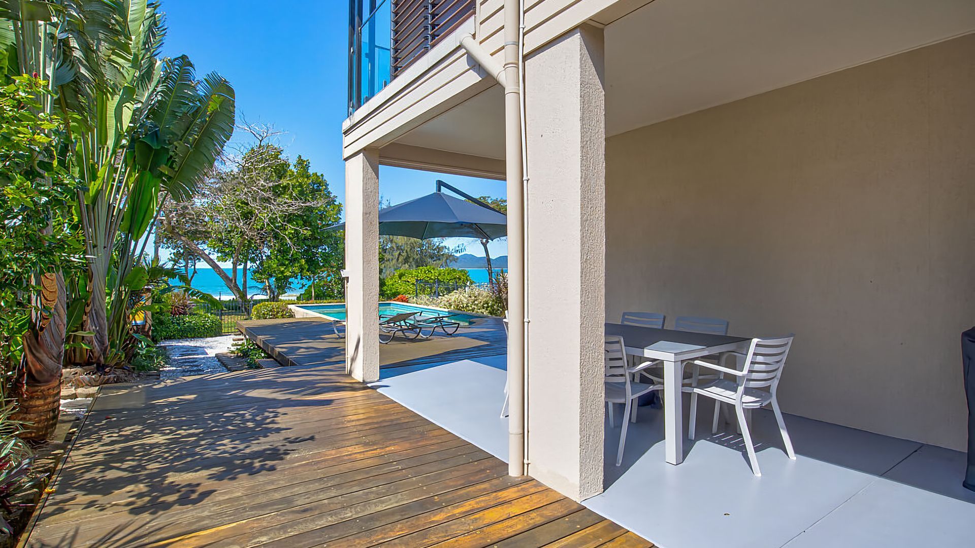 A covered outdoor area with a pool, dining table, and chairs.
