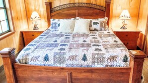 Een houten bed met een sprei, twee nachtkastjes en lampen.