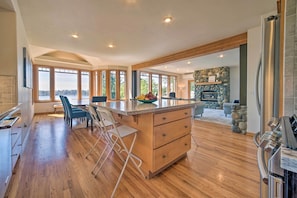 A spacious kitchen with a large island, wooden flooring, and a stone fireplace. - Spacious Lake Stevens Home w/ Fire Pit, Patio (Lake Stevens)