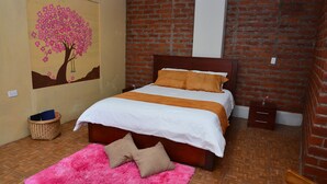 Un dormitorio con una cama de madera, un tapete rosa y un cuadro de un árbol en la pared.