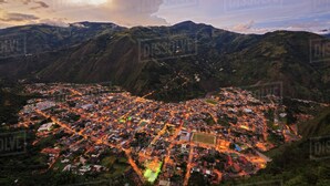 Vista aérea de un pueblo con una estructura densa de edificios, rodeado de montañas.