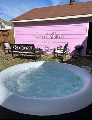 Relax in the backyard oasis, featuring a ready-to-use hot tub and comfortable seating areas.