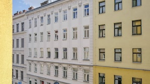 Un edificio de varios pisos con fachada blanca y amarilla, con un patrón uniforme de ventanas y una entrada central.