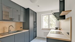 Una cocina moderna con armarios grises, encimera de madera y una ventana que deja entrar luz natural.